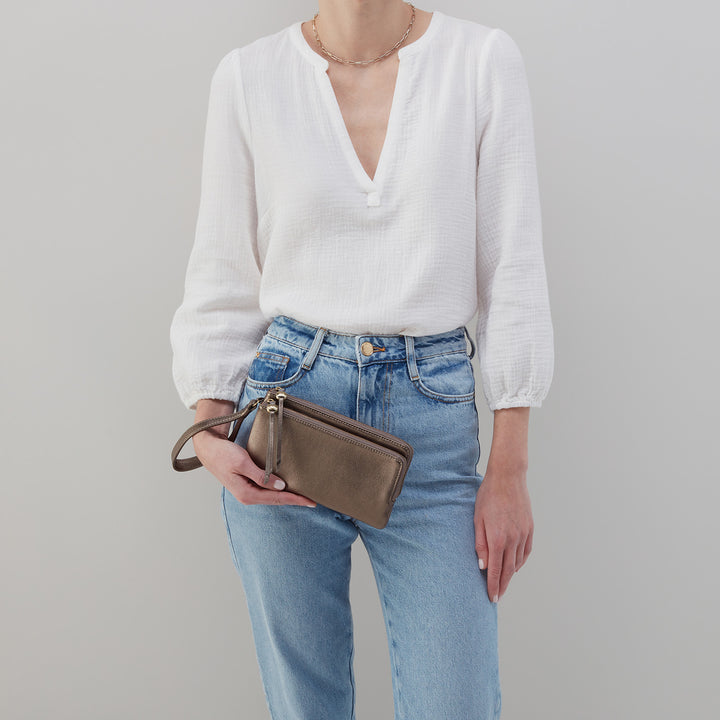 woman wearing white blouse and jeans holding pewter  Dayton Wristlet.