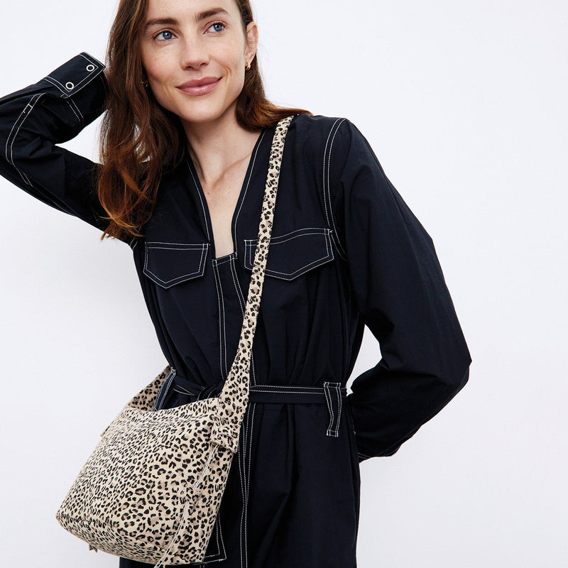 person wearing a black jumper with the leopard Bonita Crossbody over their shoulder.