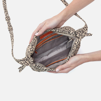 hands holding open the leopard Bonita Crossbody showing the interior.