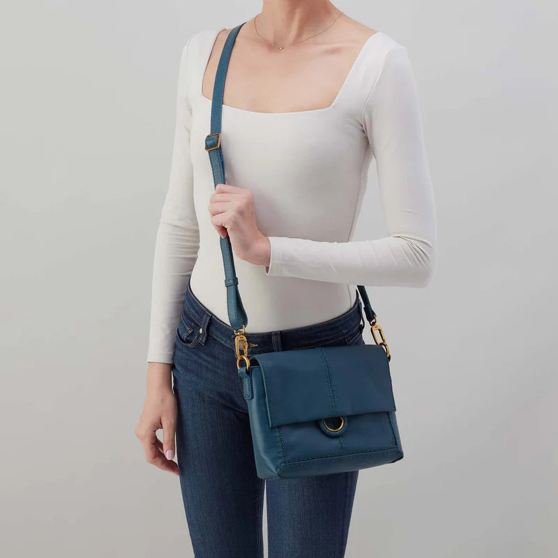 Person wearing jeans and a white top with Peacock feather austin flap crossbody over their shoulder