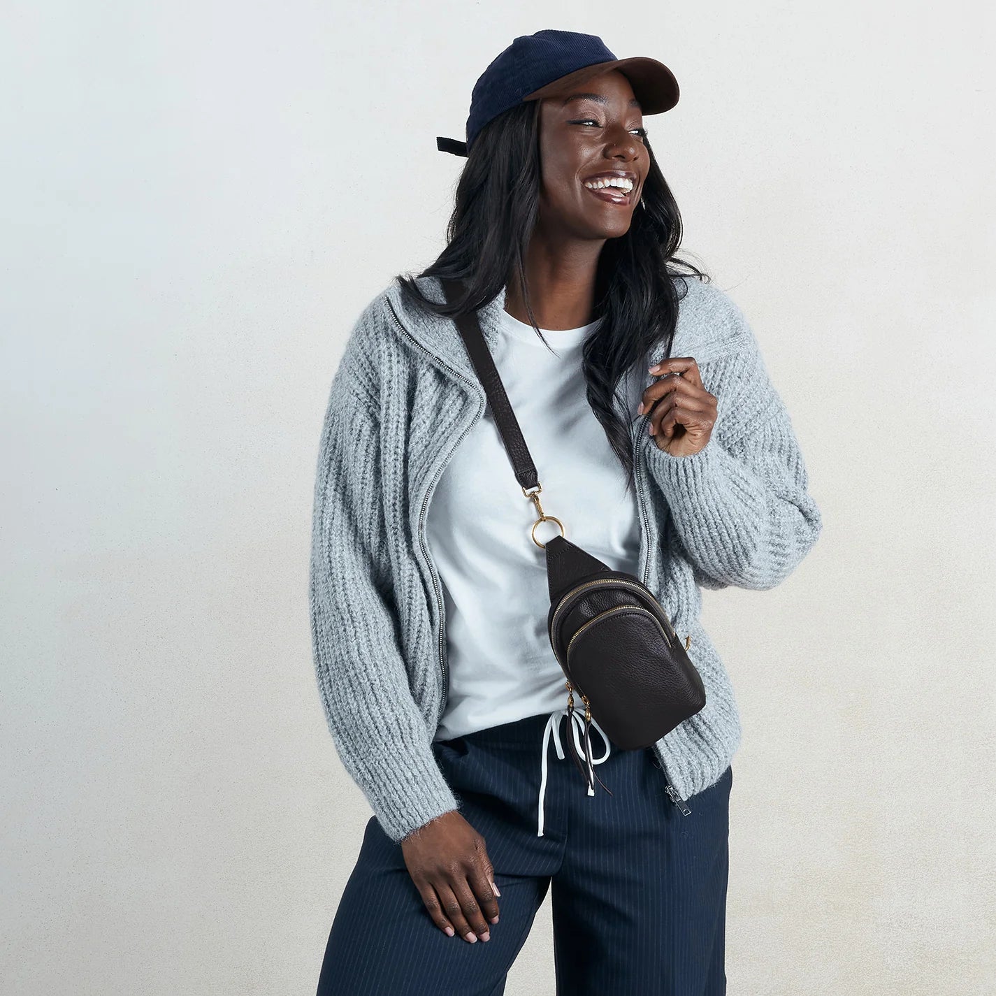 a person wearing the small fern sling bag in black on their front
