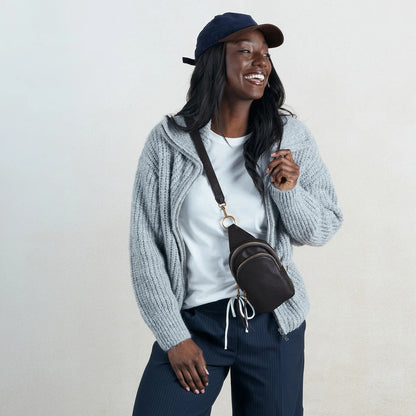 a person wearing the small fern sling bag in black on their front