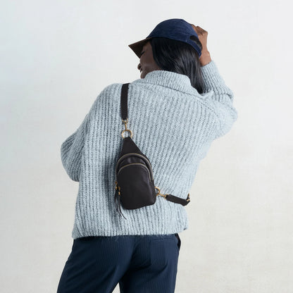a person wearing the small fern sling bag in black on their back