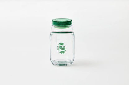 Clear glass jar with green lid on a white background