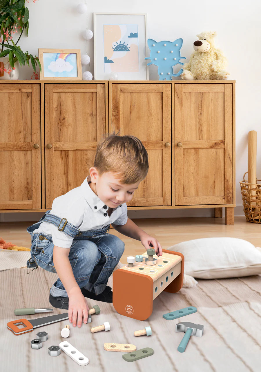 Child playing with a wooden toy tools in a room with wooden furniture and decor.