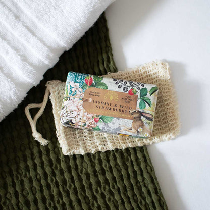 Bar of soap with floral and berry packaging on a textured green surface