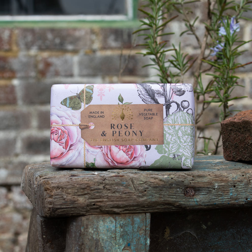 Bar of soap with floral packaging on a wooden surface outdoors