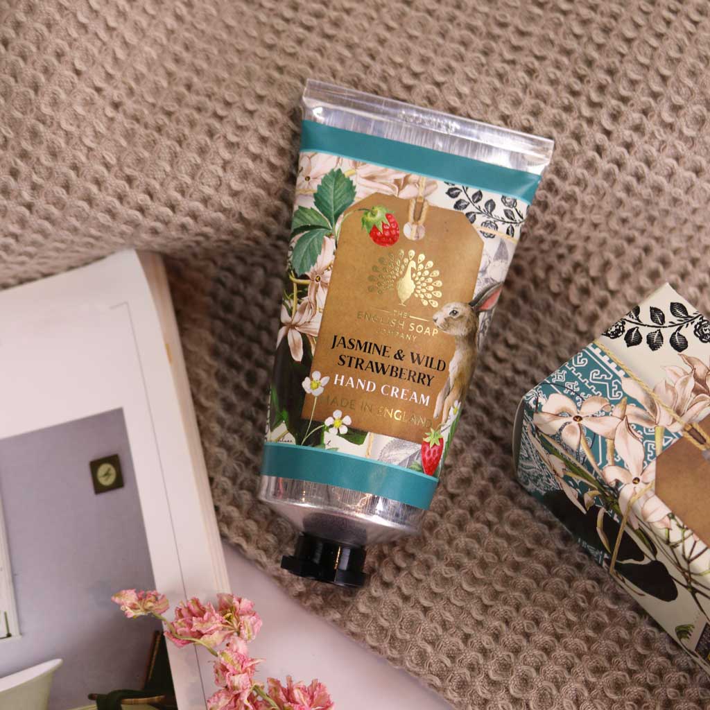 Hand cream with floral and berry packaging on a textured surface