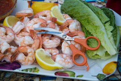 sea shrimper scissors laying on a plate of shrimp and lemon wedges
