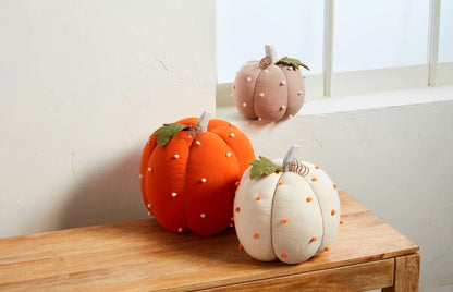 3 colors and sizes of dotted pumpkins arranged on a table with one on a window sill.