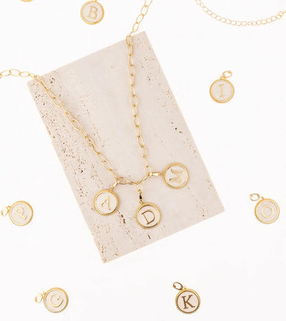 Madison Initial Charms arranged on a white background with a few charms clipped on a necklace