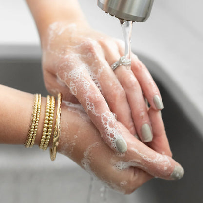 Person washing their hands and wearing a diamond ring and gold bracelets