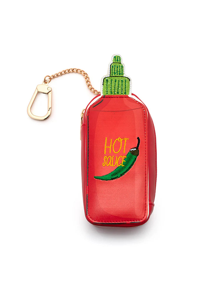 Red bag charm pouch shaped like a bottle of hot sauce with a green lid and a green pepper stitched on it with a gold chain and clip