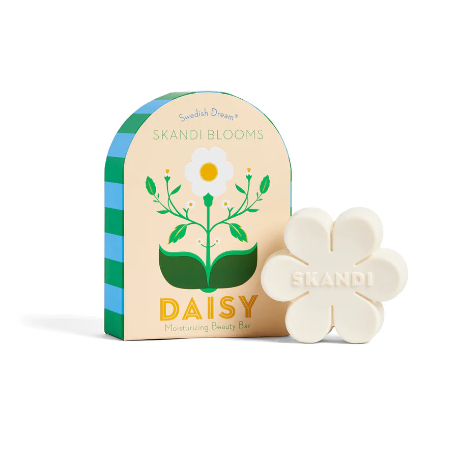Flower shaped bar of soap set next to its pale yellow box packaging with floral design.