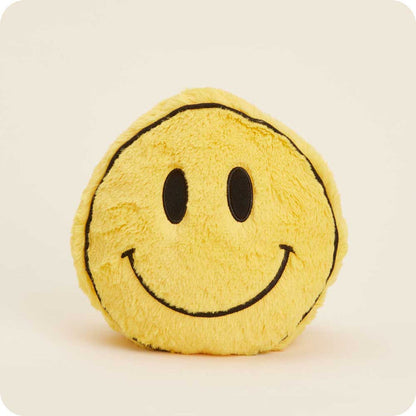 round yellow smilie face plush of a cream colored background.