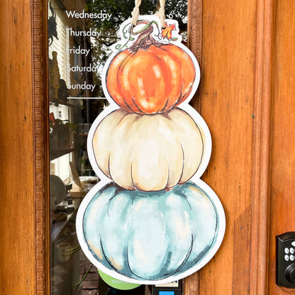 Decorativedoor hanger shaped a s a stack of 3 pumpkins, one blue, one white , and an orange one on top