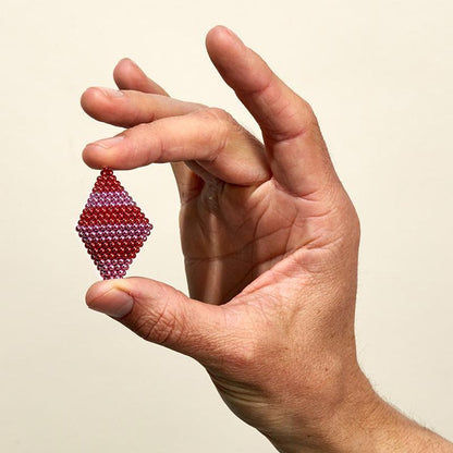 hand holding the Tones Cherry Pop magnet balls in a diamond shape against a white background