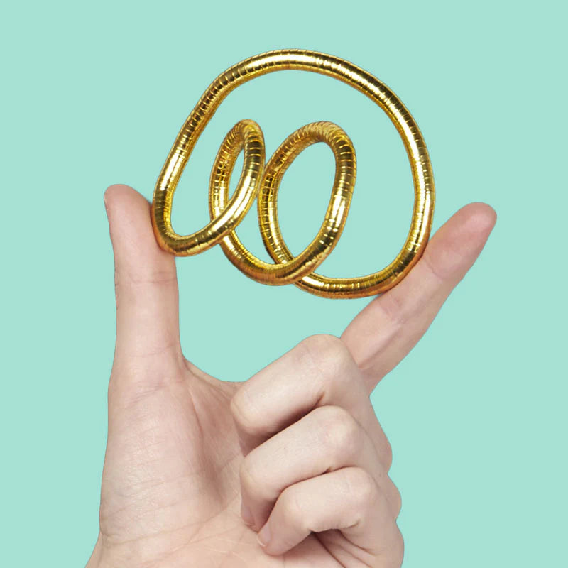 Hand holding a gold spiral fidget against a light blue background