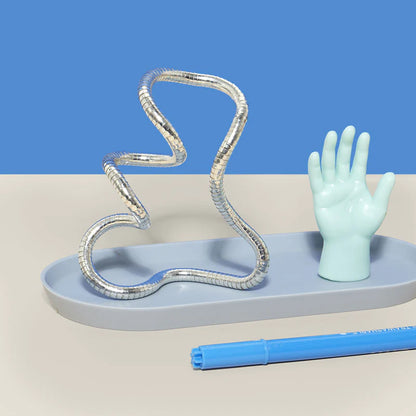 desk with silver stands fidget set on a tray with a hand figurine shown on a bright blue background