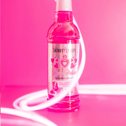 bottle of Sour Love Potion skinny syrup  on a bright pink background.