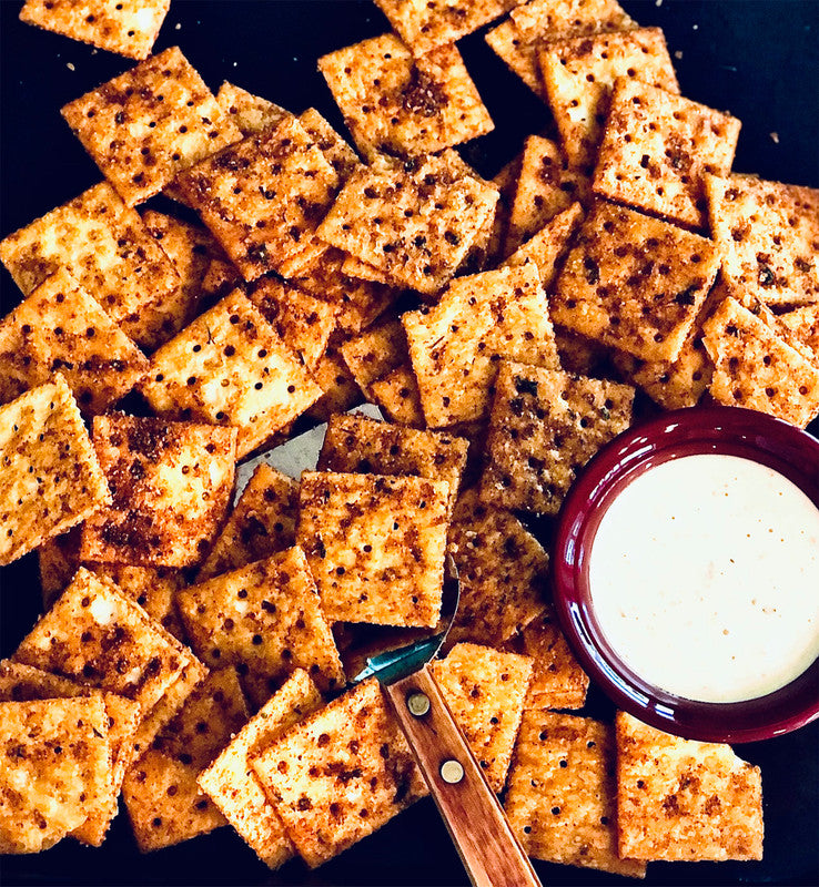 plate of crackers flavored with Sweet & Spicy Cracker Seasoning Mix set with a bowl of dip