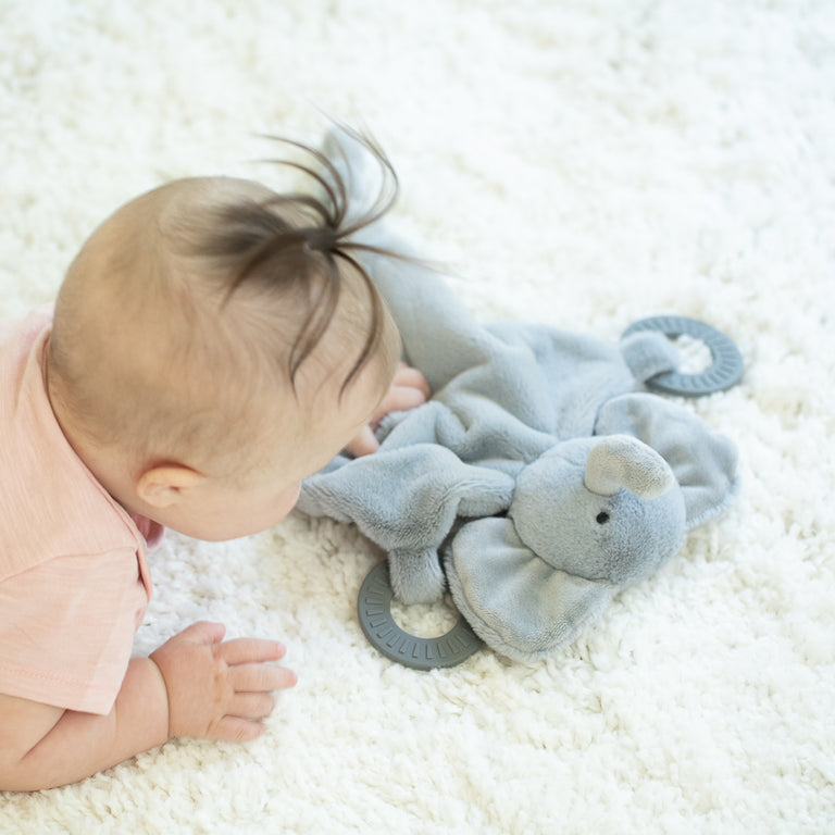 crawling baby holding elephant teether.