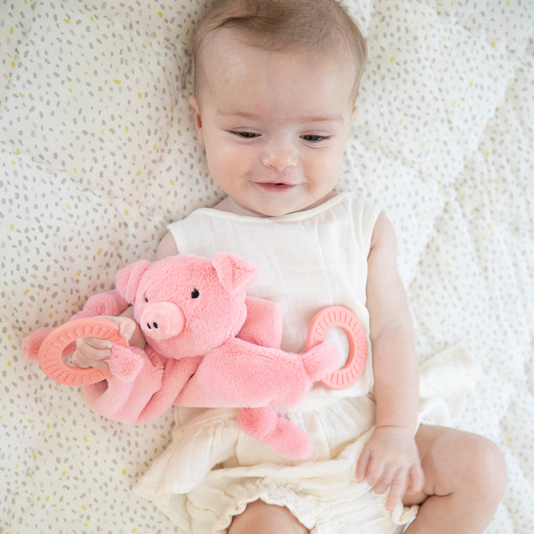 top view of child laying down holding pig teether.