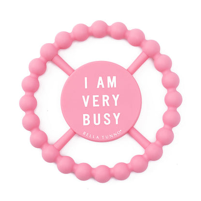 pink silicone teether with "i am vey busy" printed in white in the center.