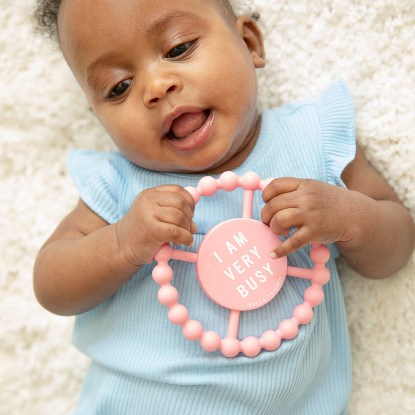 baby laying on thier back holding "busy" teether.