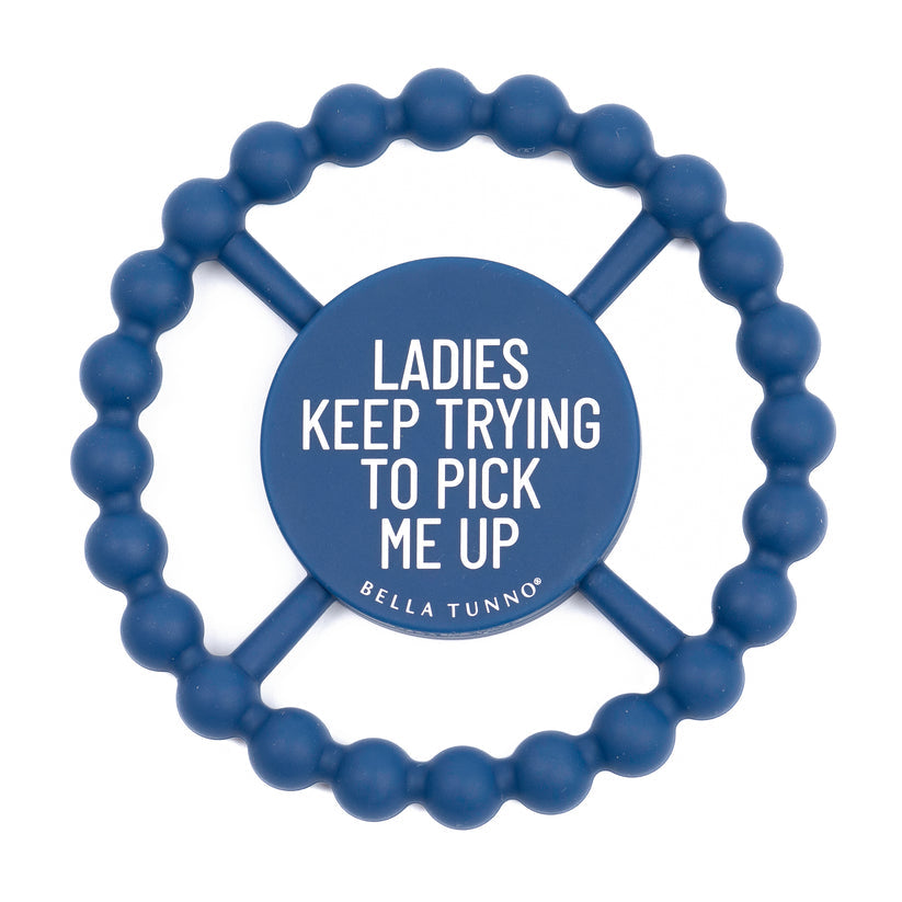 blue silicone teether with "ladies keep  trying to pick me up" printed in white in the center.