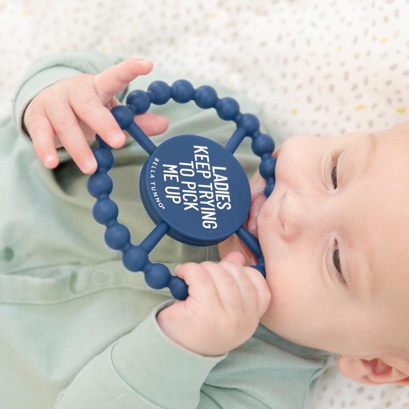 baby laying down chewing on "ladies pick me up" teether.