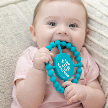 baby laying down chewing on "fun" teether.