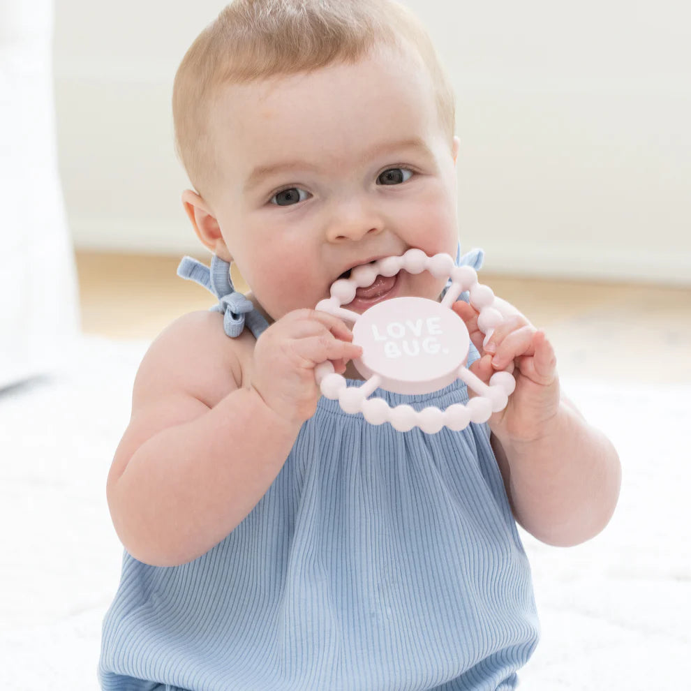 baby chewing on love bug teether.