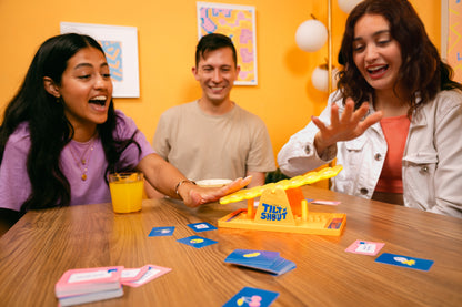  people playing the game of Tilt 'n' Shout at a table in a kitchen setting