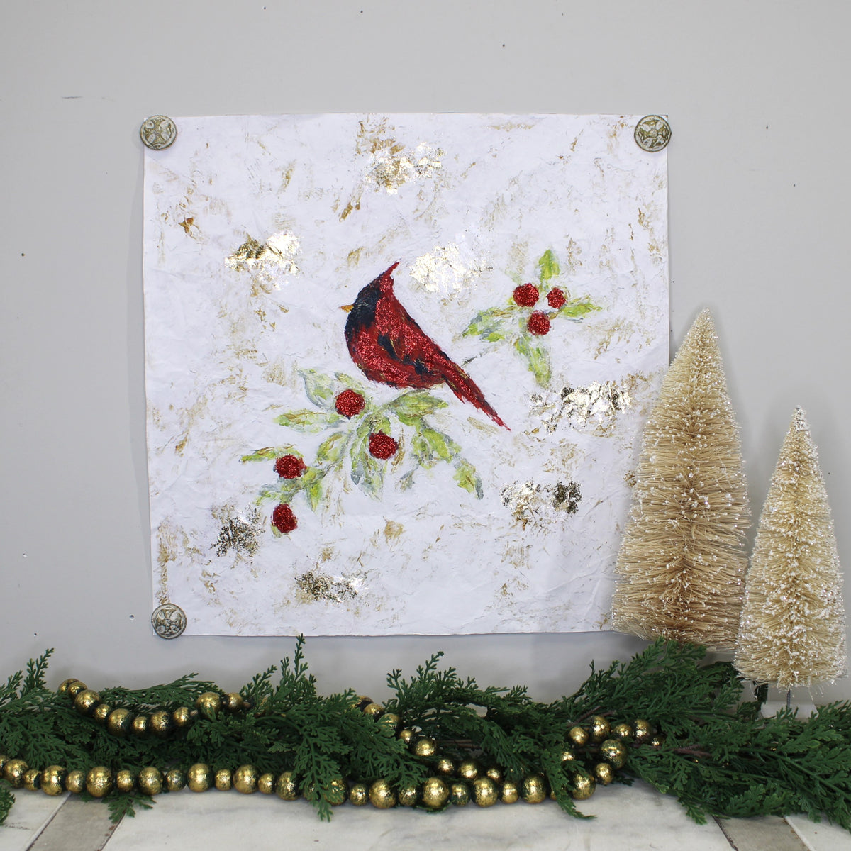 paper wall art with a red cardinal and gold details with greenery and decorations underneath