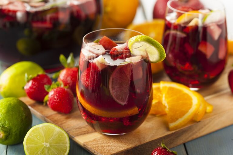 glasses filled with sangria and fruit set on a cutting board with sliced fruit.