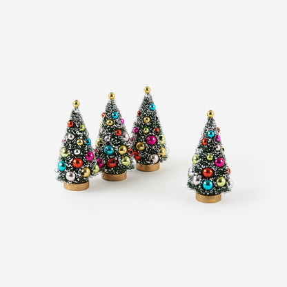 4 snow flecked bottle brush trees with ornaments on them