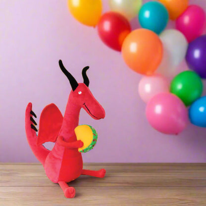 Dragons Love Tacos Plush Toy set on a table with colorful balloons in the background.
