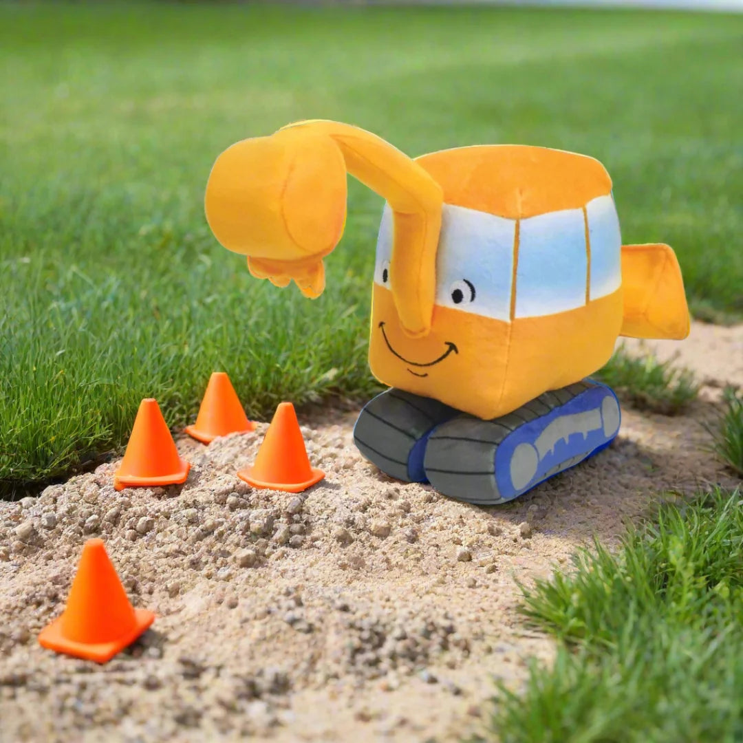 little excavator plush on a patch of sand with little cones
