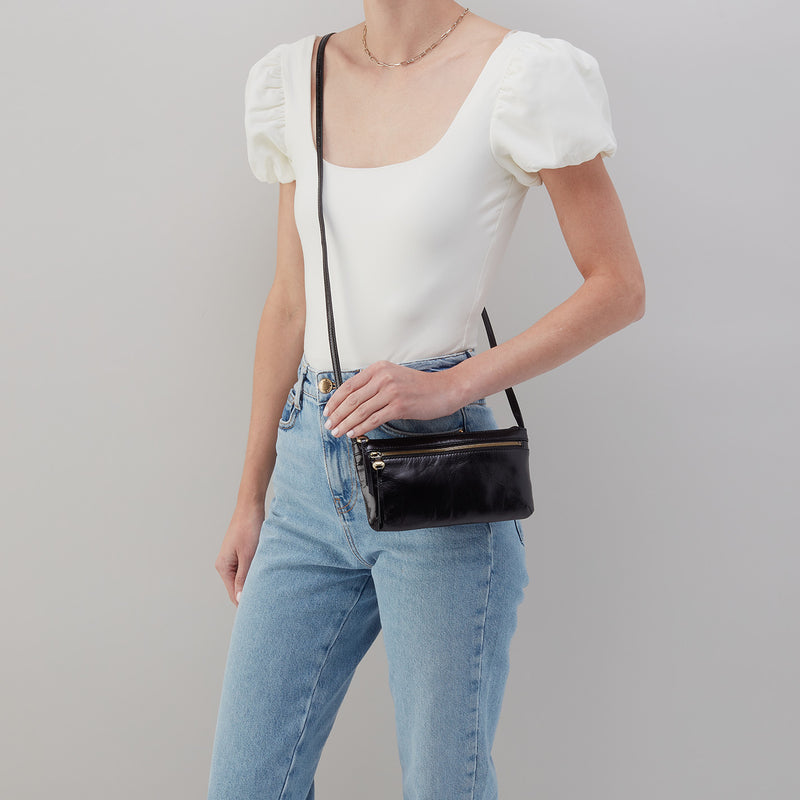 person wearing jeans and a white top with a black Cara Crossbody on their shoulder.