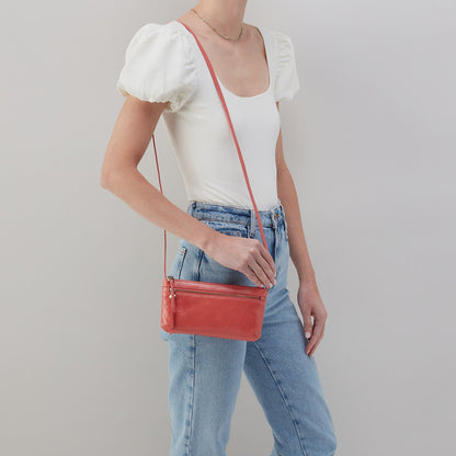person wearing jeans and a white top with the cherry blossom cara crossbody over their shoulder.