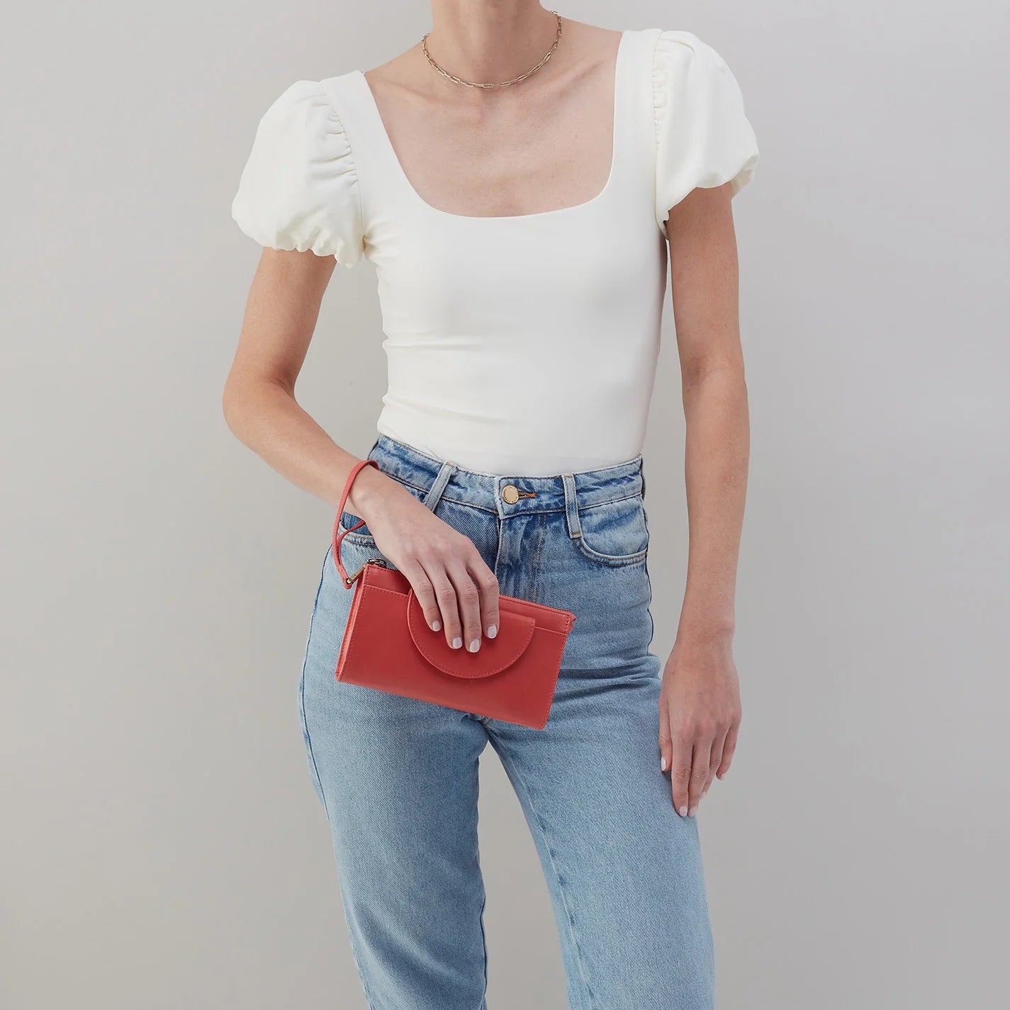 person wearing jeans and a white top holding cherry blossom zenith wristlet