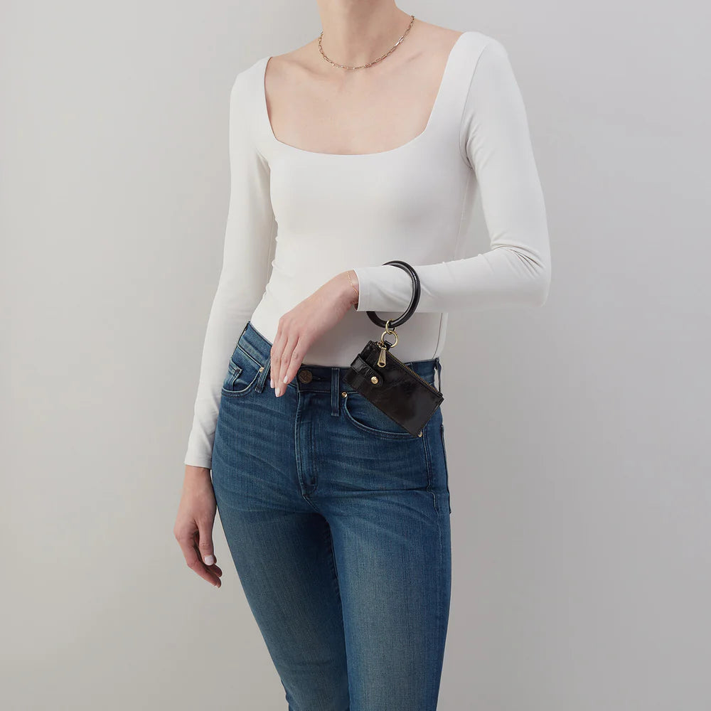 person wearing jeans and a white top with black Ring Credit Card Wristlet on their wrist.