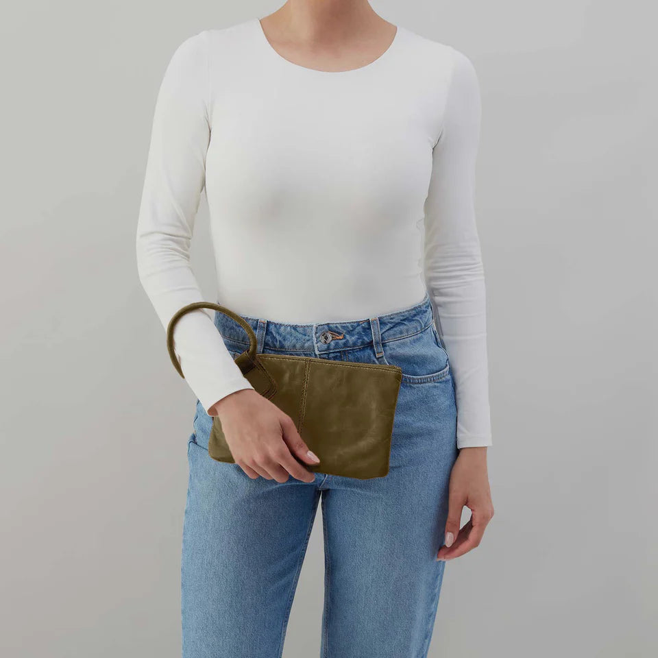 person wearing jeans and white top holding an olive green sable wristlet 