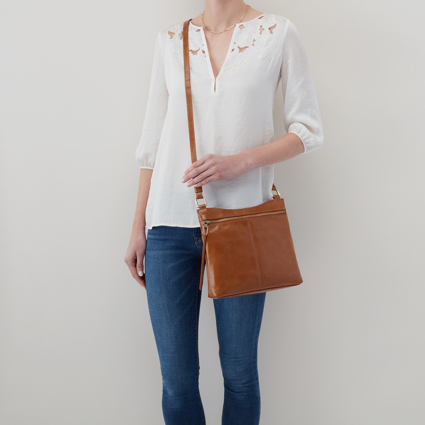 person wearing jeans and a white top with natural Cambel Crossbody over the shoulder.