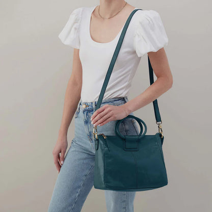 person wearing jeans and a white top with wild bluegrass Sheila Medium Satchel over their shoulder