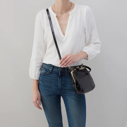 person wearing jeans and white blouse with black alba on their shoulder.