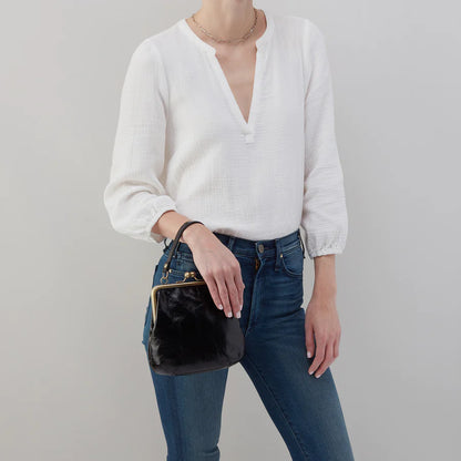 person wearing jeans and a white blouse holding black alba on their wrist.