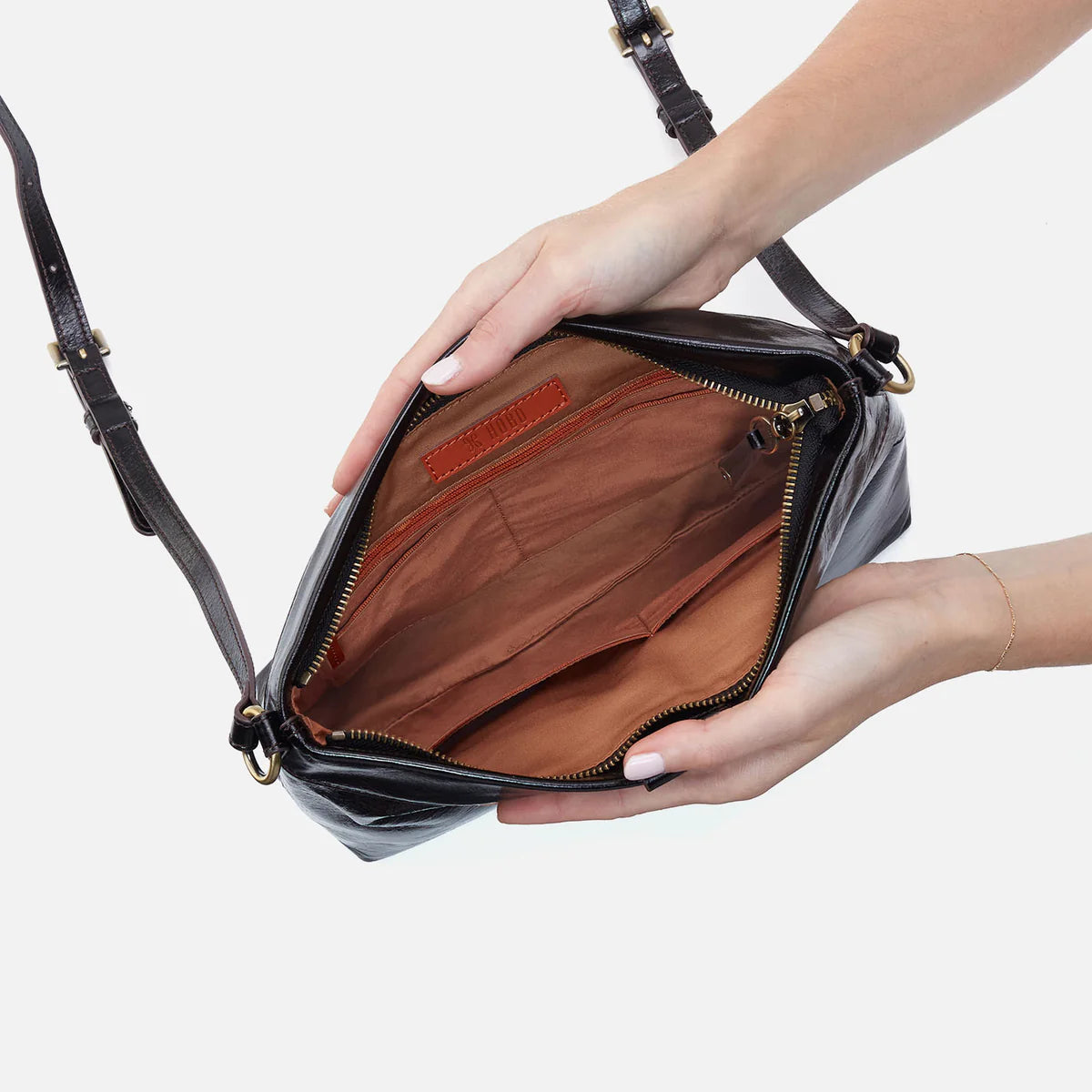person holding open the romy medium crossbody in black to show inside bag