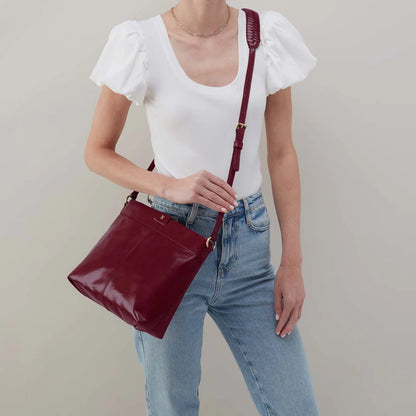 person wearing jeans and a white top with saddle berry Romy Medium Crossbody over their shoulder